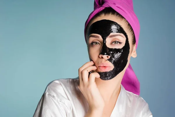 Kobieta z ręcznikiem na głowie stosowane czarne oczyszczanie maski na twarzy — Zdjęcie stockowe