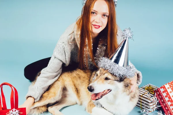 Femme heureuse dans un chapeau de Noël se trouve à côté d'un chien sur un fond de cadeau — Photo