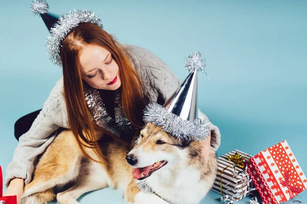 Femme dans un chapeau de Noël est assis à côté d'un chien sur un fond de cadeau — Photo