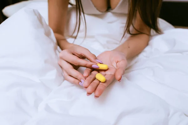 Žena sedí na posteli a drží že v ruce špunty — Stock fotografie