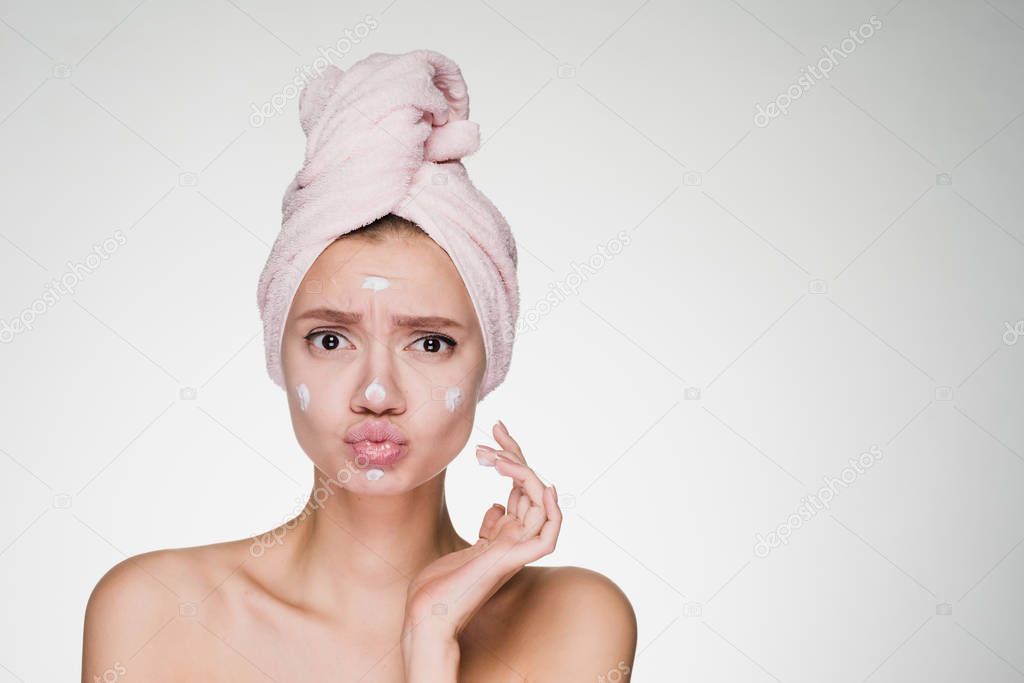 happy woman with a towel on her head applied cream on her face