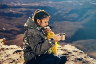 kadın turist dağlar bir arka plan üzerinde çay içer