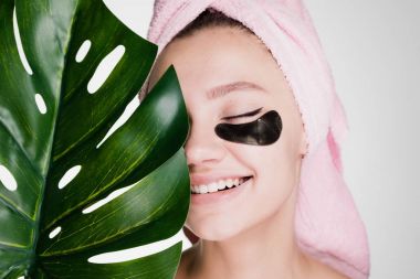 Kafasındaki bir havlu ile mutlu kadın siyah yamalar gözlerinin altında uygulanan