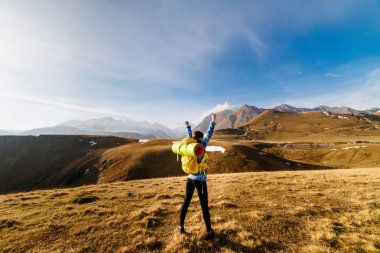 kadın turist yüksek dağlar güneşli bir arka plan üzerinde büyük bir sırt çantası ile