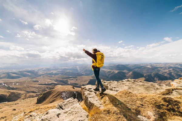 Жінка туристка з великим рюкзаком, що стоїть на тлі високих гір в сонячний день — стокове фото