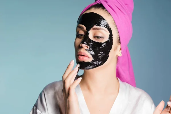 Nő fején egy törülközővel alkalmazni a fekete maszk a bőr az arcán — Stock Fotó