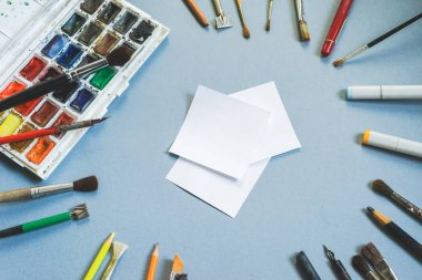 mavi bir arka plan üzerinde renkli boyalar ve fırçaları vardır