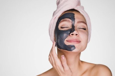 bir havlu başında kadın temizlik maskesi yüzünde uygular.