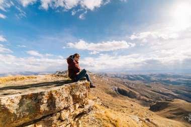 kadın turist yüksek bir dağın kenarında oturur