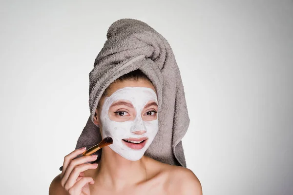 A woman in a towel on her head applied a mask to the skin of her face — Stock Photo, Image