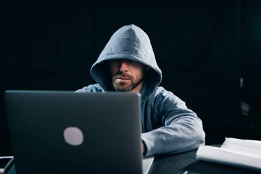 bir adam bir hacker bir kazak bir kukuleta ile'poesetsya bir dizüstü bilgisayar ve o zaman o oturuyor