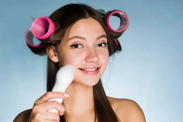 happy woman cleans the face with a brush for deep cleaning