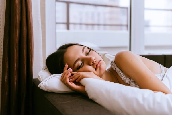 Eine Frau schläft auf einem Bett unter einer Decke — Stockfoto