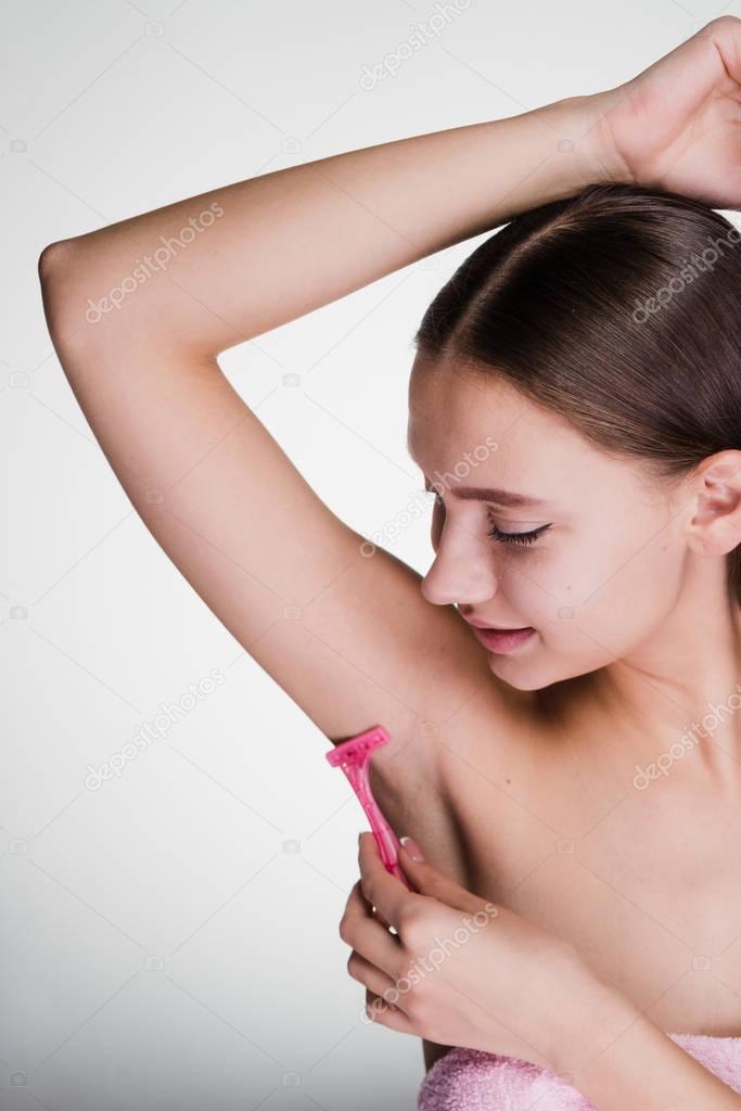a woman after the heart holds a depilation of armpits with a razor