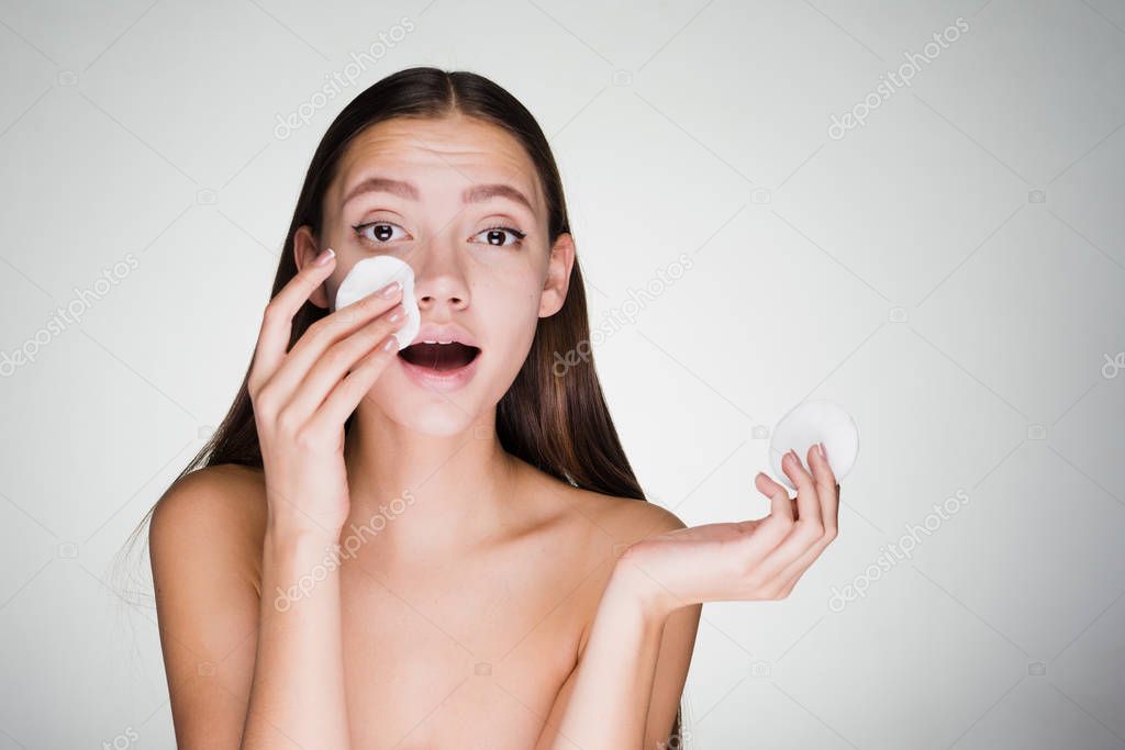woman removes makeup with a cotton disc