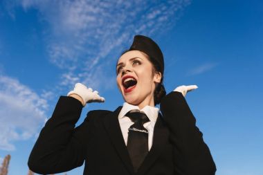 Mavi gökyüzüne karşı üniformalı kadın hostes.