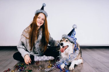 Festival şapkalı mutlu kadın köpek yanında oturur
