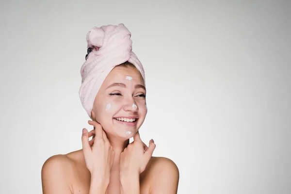 Happy woman with a towel on her head applied cream on her face — Stock Photo, Image