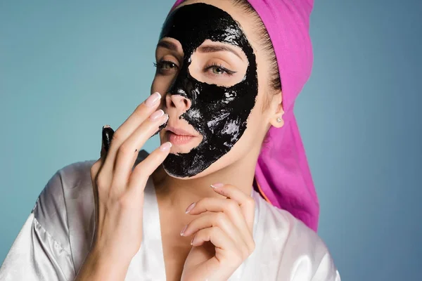 Γυναίκα με μια πετσέτα στο κεφάλι της Εφαρμόστε μια καθαριστική μάσκα στο πρόσωπό της — Φωτογραφία Αρχείου