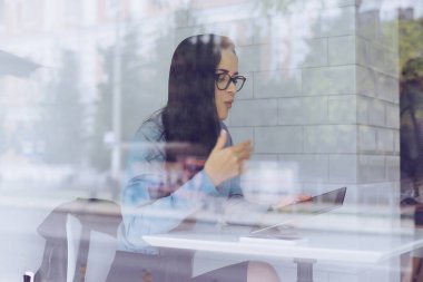 kadının gözünde camın ardında oturuyor ve tablet vasıl görünüyor
