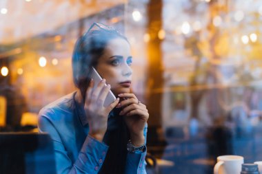 telefonda konuşurken cam arkasında dalgın kadın