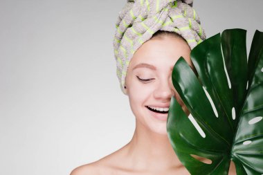 Kafasındaki bir havlu ile mutlu kadın büyük bir yaprak tutar