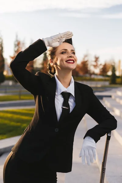 Letuška šťastná žena v uniformě se dívá na nebe — Stock fotografie