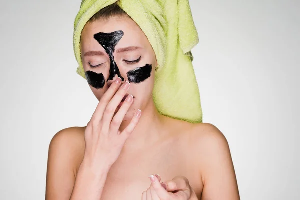 A woman with a towel on her head puts a mask on problem areas — Stock Photo, Image
