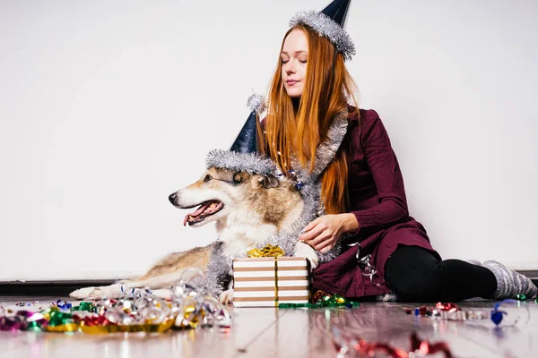 Счастливая женщина в рождественской шляпе на голове, сидящая рядом с собакой — стоковое фото