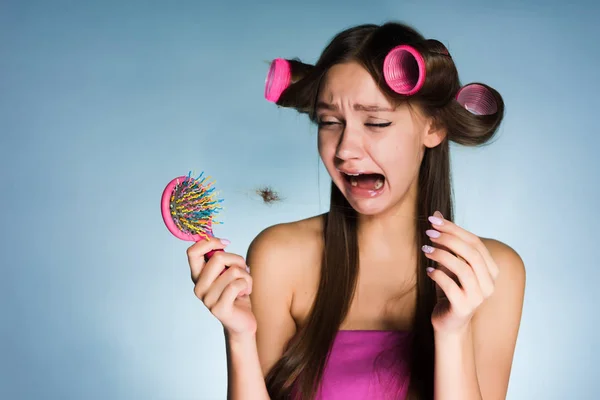 Расстроенная женщина из-за выпадения волос с бигуди на голове — стоковое фото