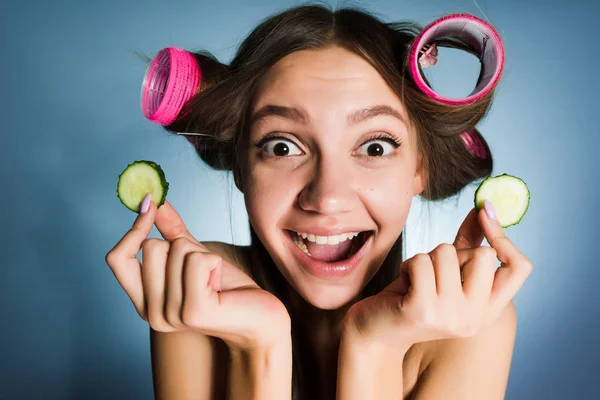 Šťastná žena s natáčky na hlavě drží okurky ve svých rukou — Stock fotografie