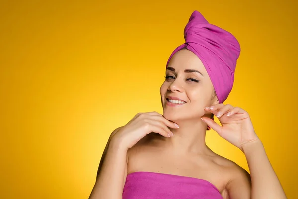 Lycklig kvinna med en handduk på huvudet mot gul bakgrund — Stockfoto