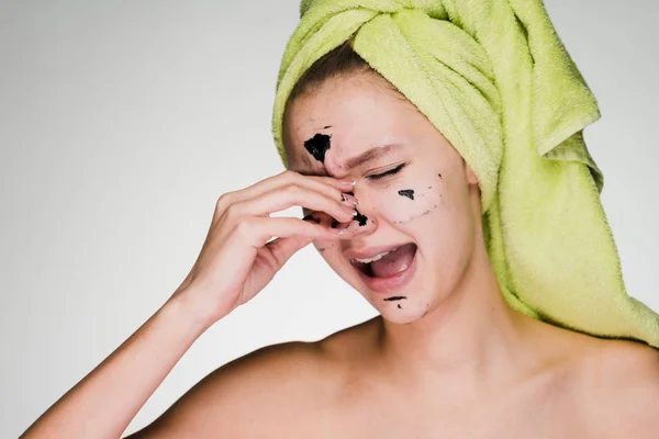 Женщина с полотенцем на голове снимает маску с лица — стоковое фото