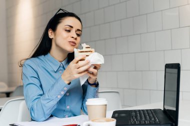 kadını masada oturan ve bir sandviç yeme