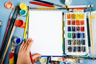 çok renkli boyalar bir arka plan karşı bir tasarım defter yatıyor