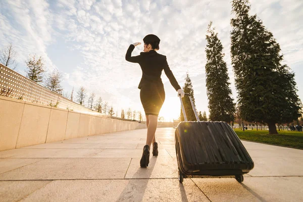 woman in flight stewardess carries a large suitcase