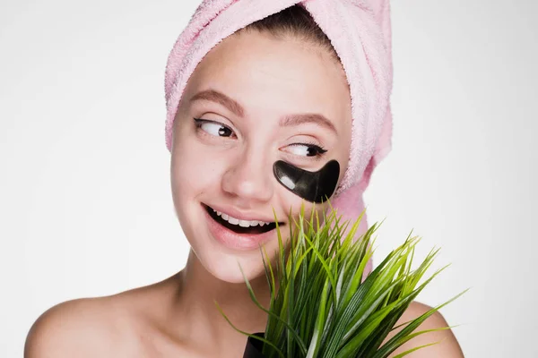 Lycklig kvinna med en handduk på huvudet håller i sin hand växt i kruka — Stockfoto