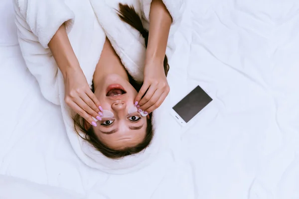 Женщина лежит на кровати и положил под глазами заплаты — стоковое фото