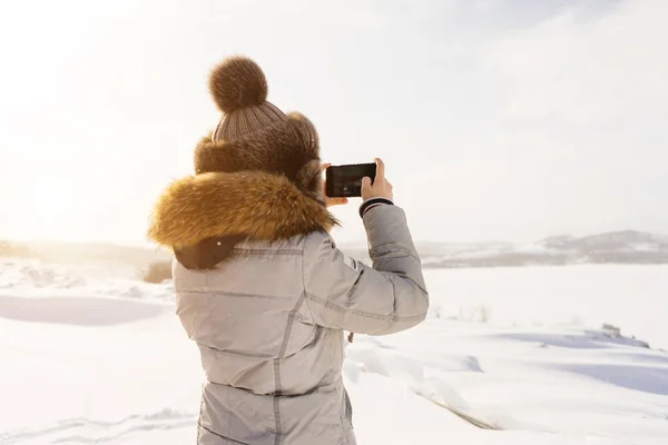 Kobieta jest fotografowanie w telefonie pole pokryte śniegiem — Zdjęcie stockowe