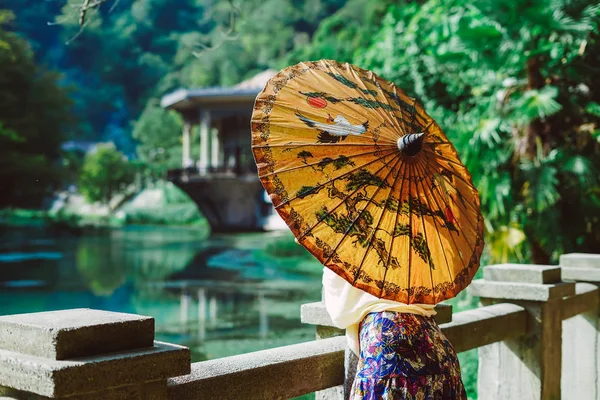 Mujer sostiene un paraguas en su mano y mira al lago — Foto de Stock