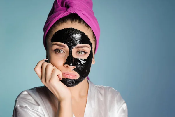 Kobieta z ręcznikiem na głowie zastosować czarna maska na twarzy skóry — Zdjęcie stockowe
