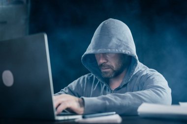 bir dizüstü bilgisayar arkasındaki karanlık bir odada oturan adam hacker