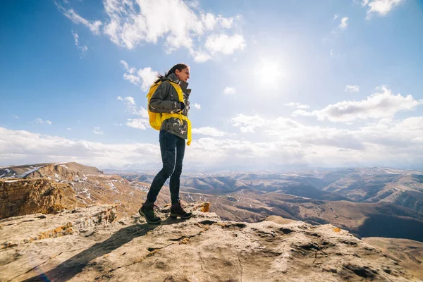 Туристка с рюкзаком, стоящим на скале на фоне высоких гор — стоковое фото