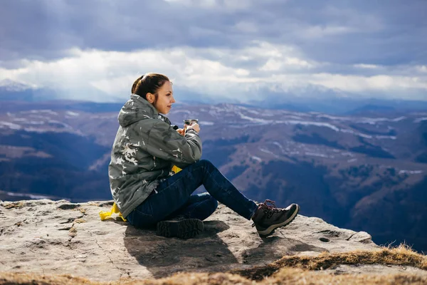 Turista mujer bebe té sobre un fondo de montañas —  Fotos de Stock