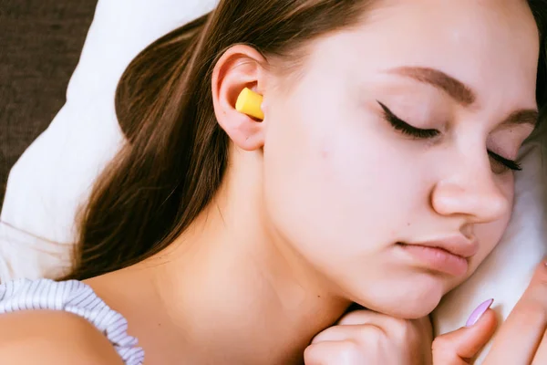 Kobieta leży śpiące w łóżku z zatyczki do uszu w uszach — Zdjęcie stockowe
