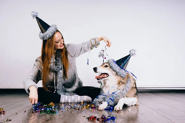 Une femme dans une casquette festive s'assoit à côté d'un chien — Photo
