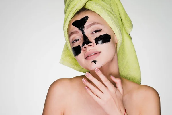 Γυναίκα με μια πετσέτα στο κεφάλι της εφαρμόζεται μια μαύρη μάσκα για να καθαρίσετε το δέρμα του προσώπου στις προβληματικές περιοχές — Φωτογραφία Αρχείου