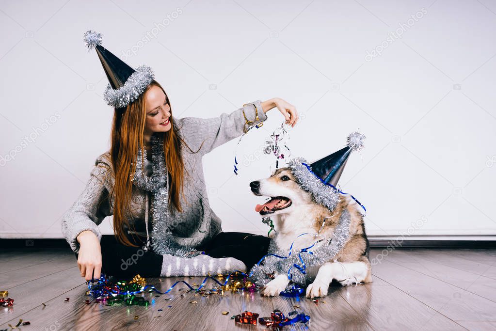 a woman in a festive cap sits next to a dog