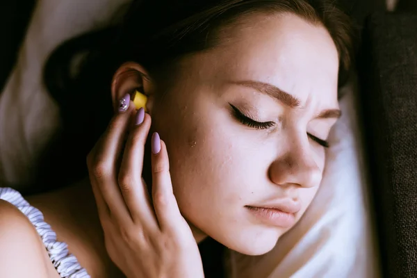 Frau schläft auf dem Bett mit Ohrstöpseln in den Ohren — Stockfoto