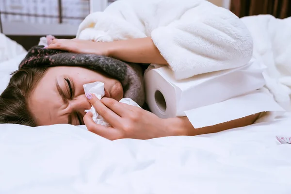 A sick woman lies on the bed next to a paper towel — Stock Photo, Image